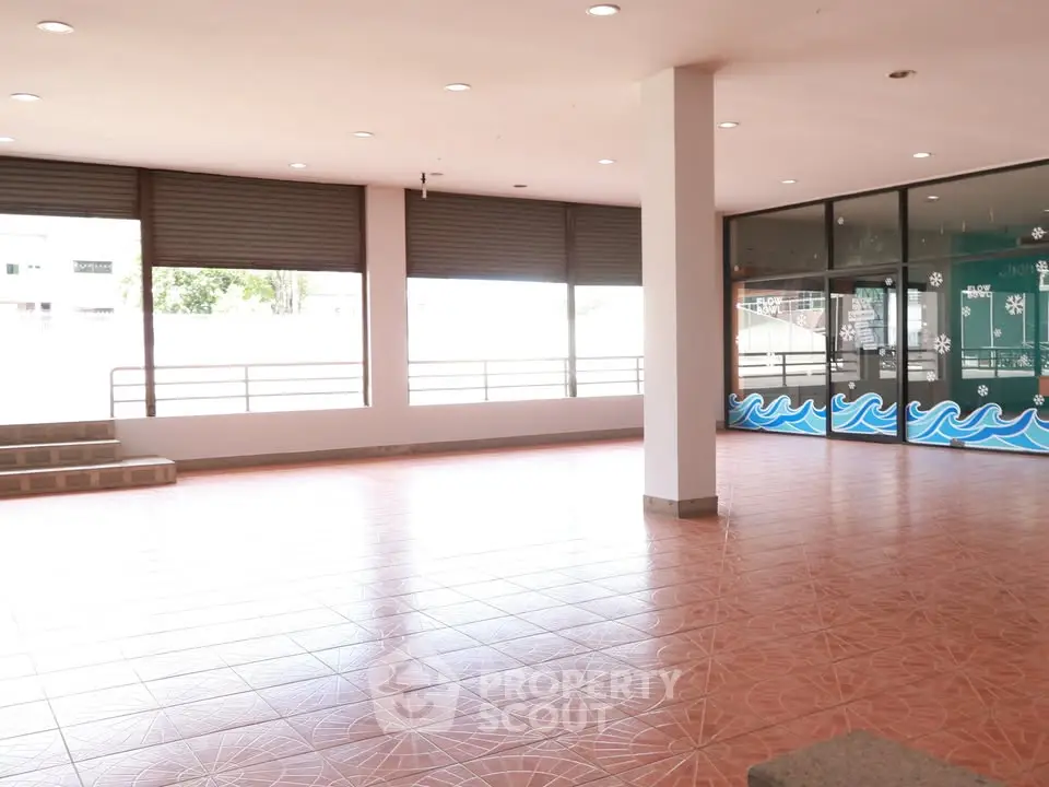 Spacious open area with tiled flooring and large windows, ideal for commercial use.