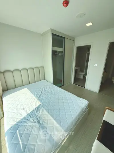 Modern bedroom with minimalist design and ensuite bathroom in a bright apartment.