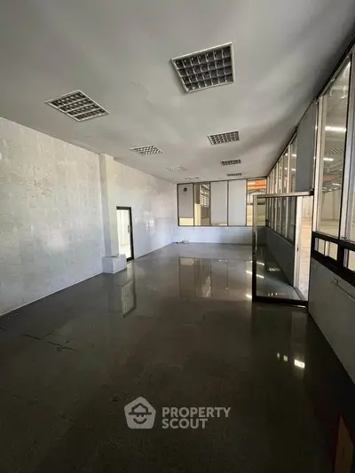 Spacious empty office space with large windows and tiled flooring, ideal for customization.