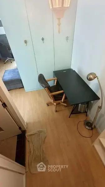 Cozy study area with desk, chair, and lamp in a compact apartment setting.