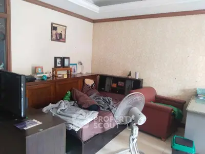 Cozy living room with sofa, fan, and TV, ideal for relaxation and entertainment.