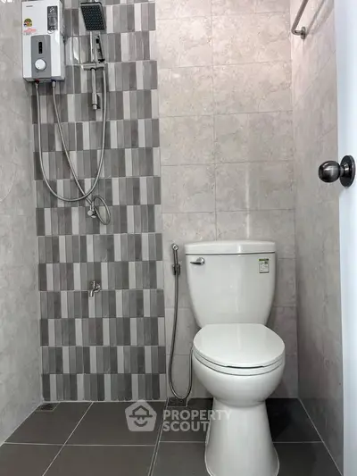 Modern bathroom with sleek tiles and shower heater in a contemporary home.