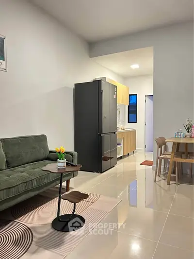 Modern living room with sleek furniture and open kitchen layout, featuring a stylish fridge and cozy seating area.