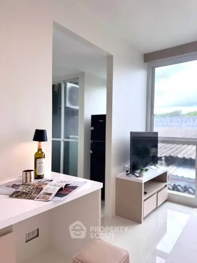 Modern living room with sleek furniture and large window offering natural light and scenic view.