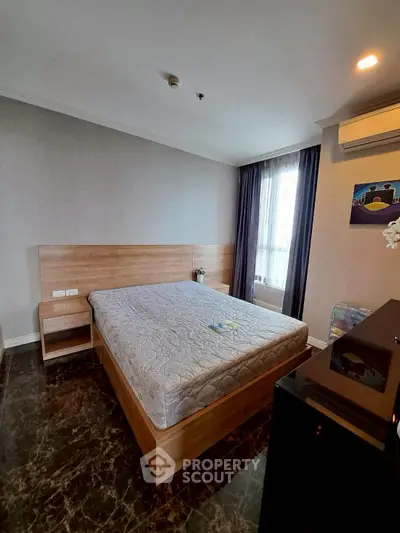 Spacious bedroom with modern decor and large window offering natural light.