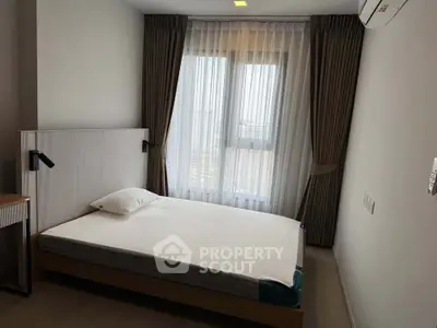 Modern bedroom with large window and minimalist decor in a high-rise apartment.