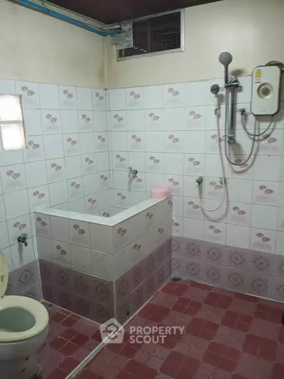 Functional bathroom with tiled walls and floor, featuring a shower and toilet, ideal for practical living.