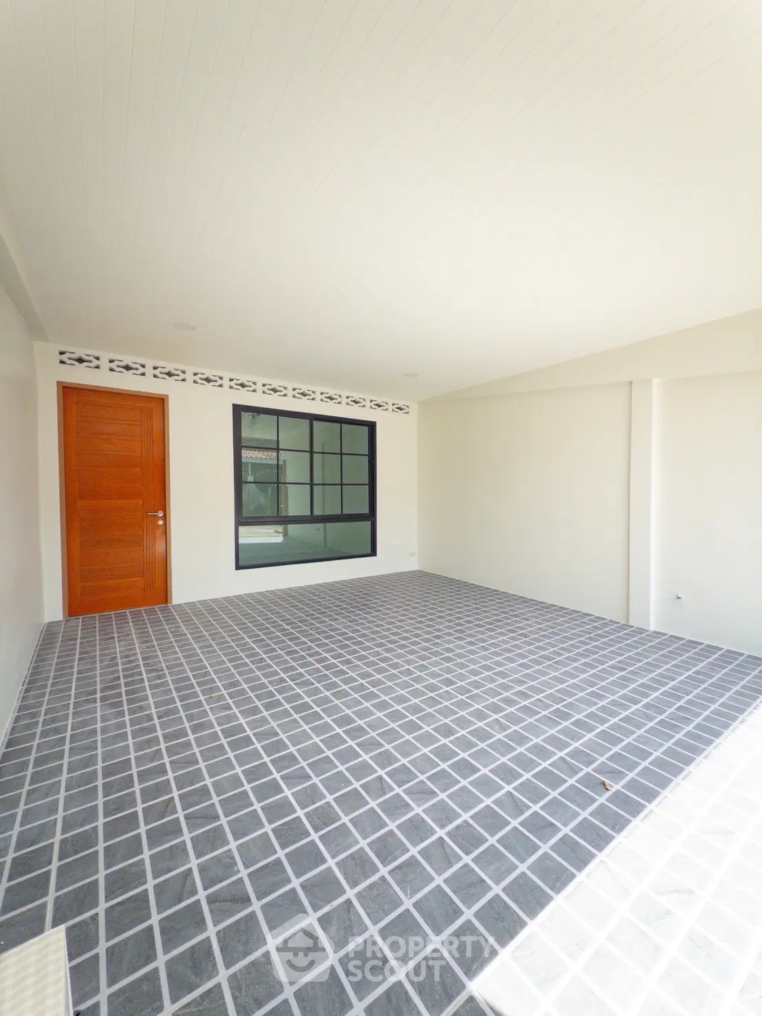 Spacious modern room with tiled floor and wooden door, perfect for versatile use.