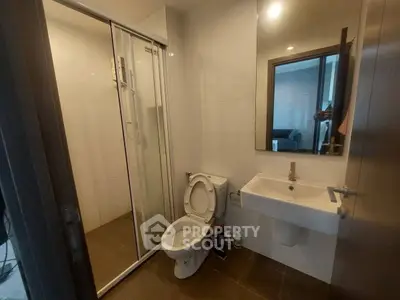 Modern bathroom with glass shower and sleek fixtures in contemporary apartment.