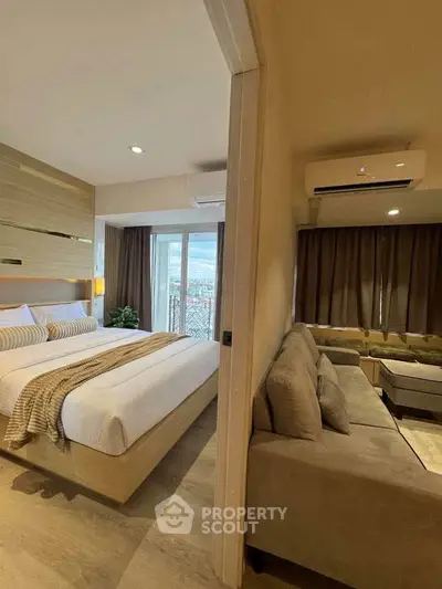 Modern bedroom with cozy living area and city view, featuring stylish decor and natural light.