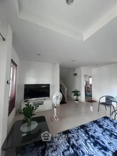 Spacious living room with modern decor and natural light, featuring a cozy seating area and stylish furnishings.