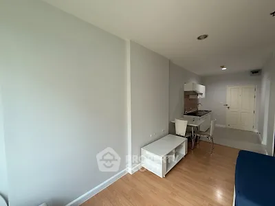 Modern apartment interior with compact kitchen and dining area, featuring sleek design and wooden flooring.