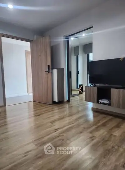 Modern living room with wooden flooring and sleek TV unit in a stylish apartment.