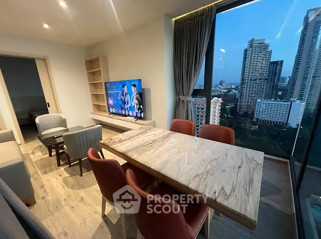 Modern living room with city view, stylish furniture, and large TV in high-rise apartment.