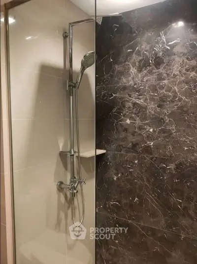 Luxurious bathroom with elegant marble shower wall and modern fixtures.