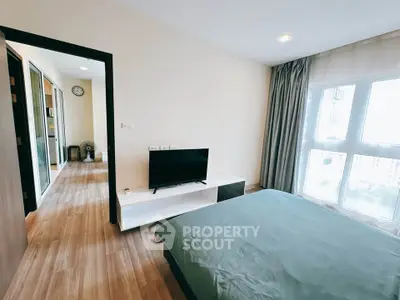 Spacious bedroom with modern decor and large window offering natural light.