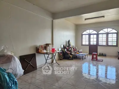 Spacious living room with tiled flooring and natural light from large windows.