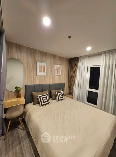 Cozy bedroom with modern decor, featuring a large bed, stylish artwork, and a small desk area.