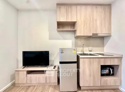 Modern compact kitchen with integrated appliances and sleek wooden cabinetry in a cozy apartment.