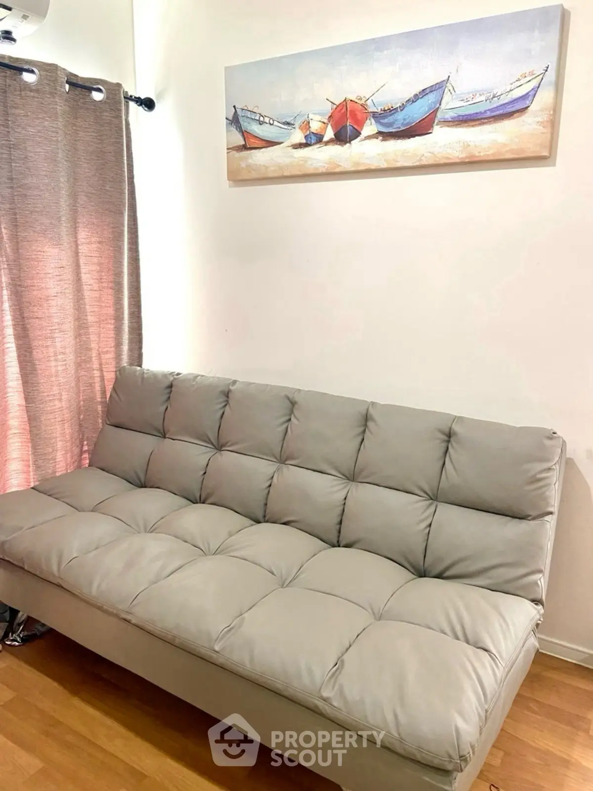 Stylish living room with modern gray sofa and boat-themed wall art.