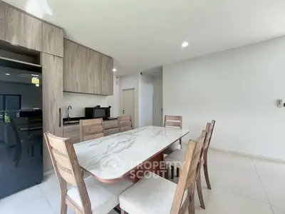 Modern dining area with sleek marble table and wooden chairs in a bright open kitchen layout.