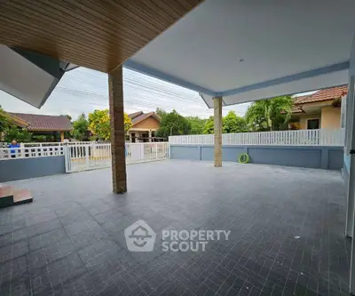 Spacious covered patio with tiled flooring and garden view in suburban home