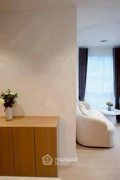 Modern living room with elegant white sofa and large window with curtains, featuring a minimalist wooden cabinet.