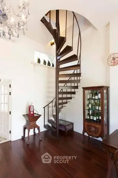 Elegant spiral staircase in a stylish living room with wooden floors and vintage decor.