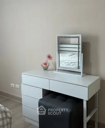 Modern bedroom dresser with mirror and flower vase in stylish interior.
