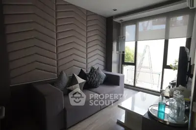 Modern living room with stylish decor and large window offering natural light.