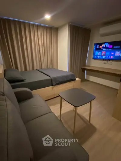 Modern studio apartment with cozy bed, sofa, and wall-mounted TV, perfect for urban living.