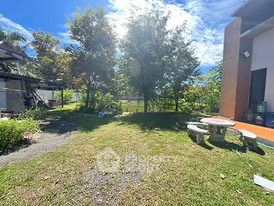 Spacious backyard with lush greenery and outdoor seating area under clear blue sky.