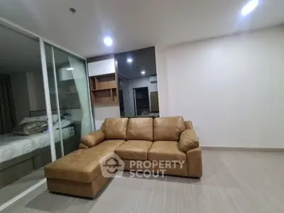 Modern living room with stylish brown leather sectional sofa and sleek wooden flooring.