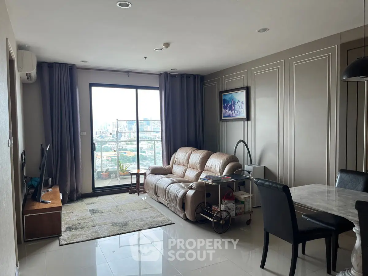 Modern living room with leather sofa and city view balcony in high-rise apartment.