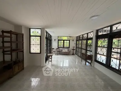 Spacious sunlit living room with large windows and elegant tiled flooring