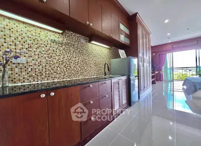 Spacious kitchen with modern cabinetry and mosaic backsplash in open layout apartment.