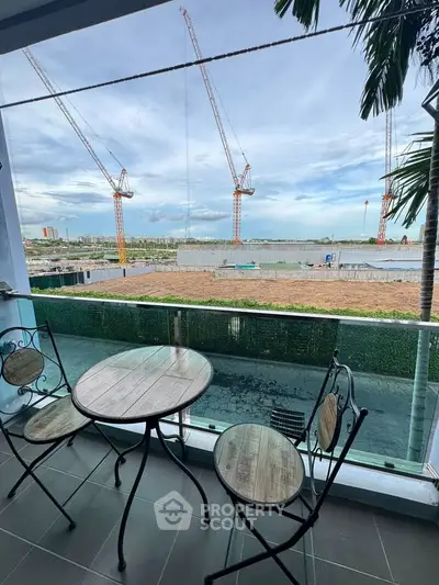 Charming balcony with stylish furniture overlooking construction site and skyline views.