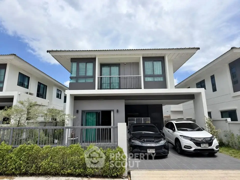 Modern two-story house with sleek design and spacious driveway in a suburban neighborhood.