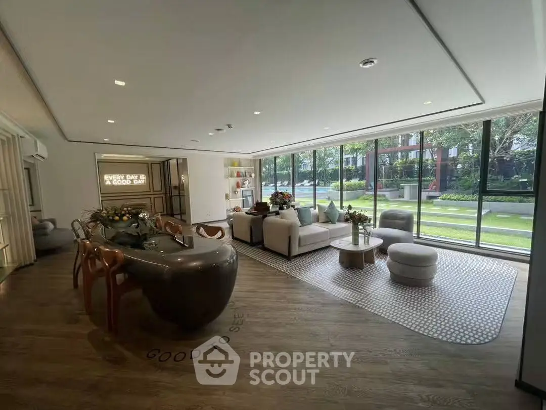 Spacious modern living room with large windows and elegant decor, offering a serene garden view.