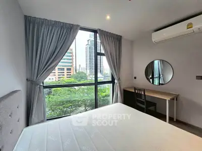 Modern bedroom with large window, city view, and stylish furnishings in urban apartment.