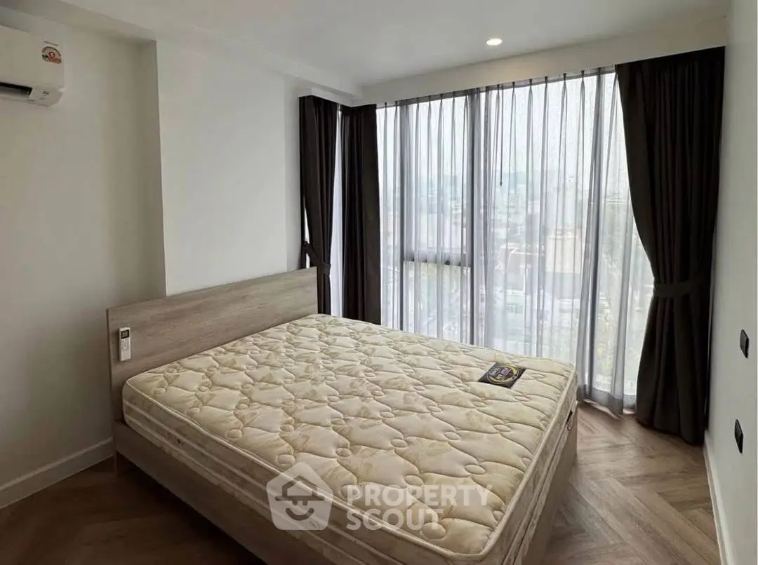 Spacious bedroom with large windows and natural light in modern apartment.