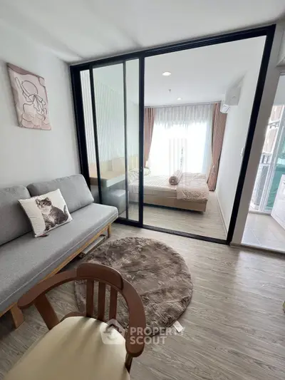 Modern studio apartment with cozy living area and bedroom separated by glass sliding doors.