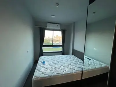 Modern bedroom with large window and city view, featuring a comfortable mattress and air conditioning.