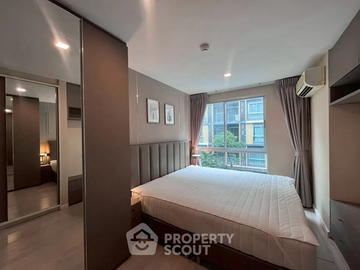 Modern bedroom with large window and stylish decor in a contemporary apartment.