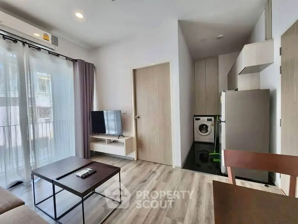 Modern living room with TV, washing machine, and balcony access in a stylish apartment.