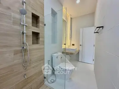Modern bathroom with glass shower and sleek fixtures, featuring a minimalist design.