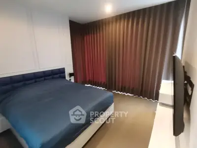 Spacious bedroom with a large comfortable bed, elegant dark curtains, and a mounted flat-screen TV, perfect for relaxation.