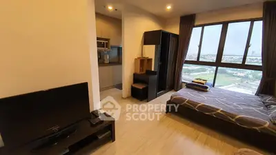 Modern studio apartment with city view, featuring cozy living area and compact kitchen.