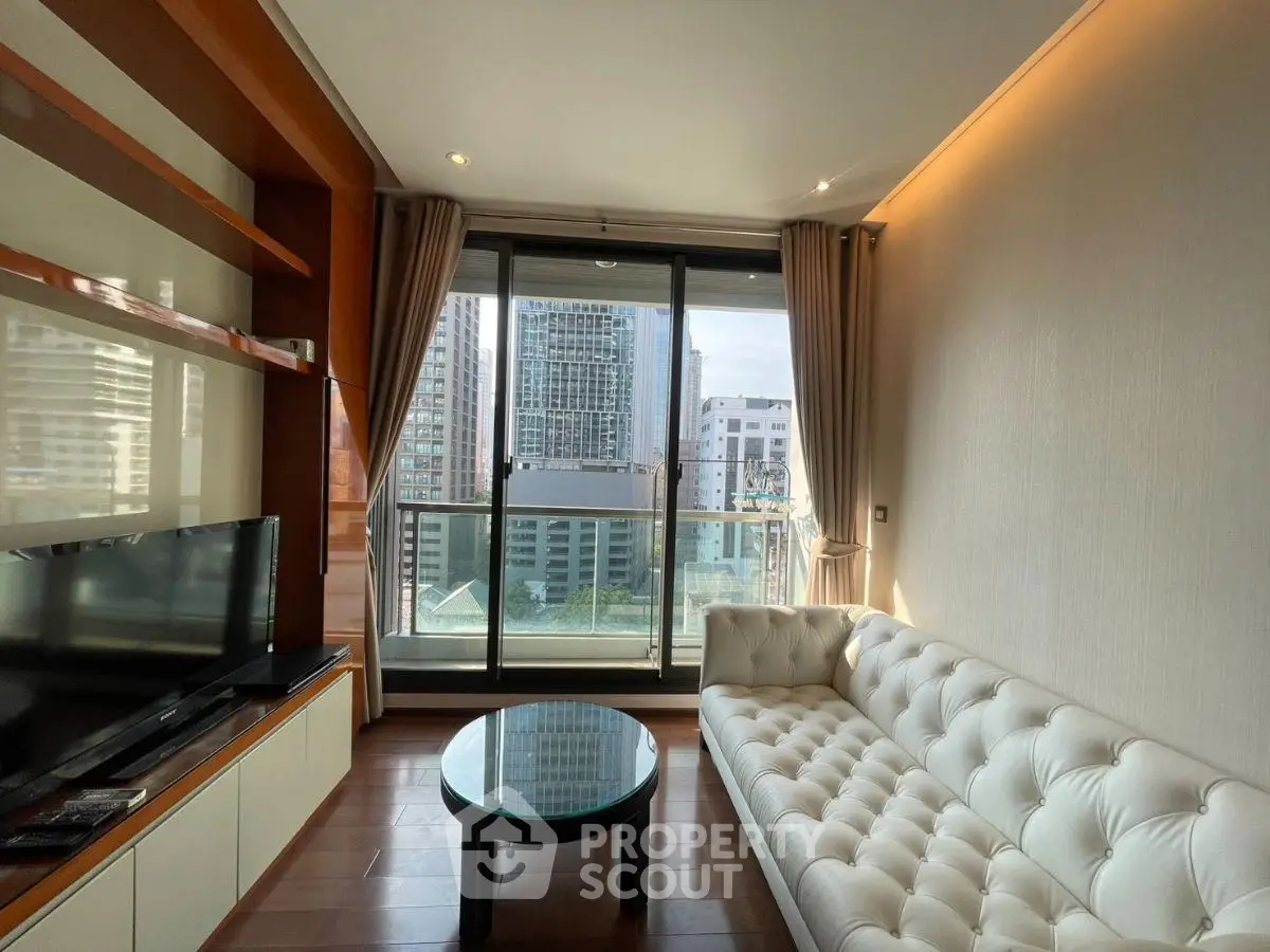 Modern living room with large window offering stunning city view, featuring elegant white sofa and sleek TV unit.