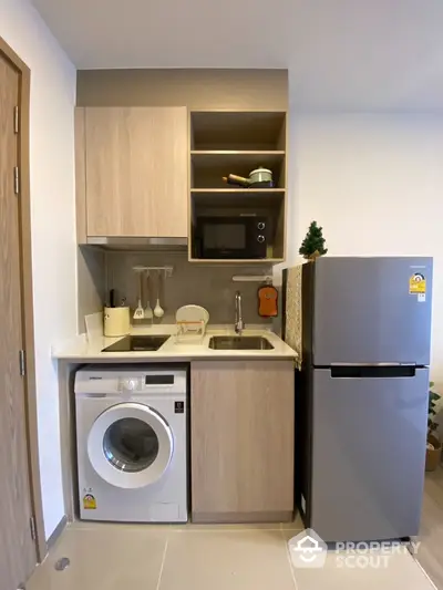 Modern compact kitchen with washing machine and fridge in a stylish apartment